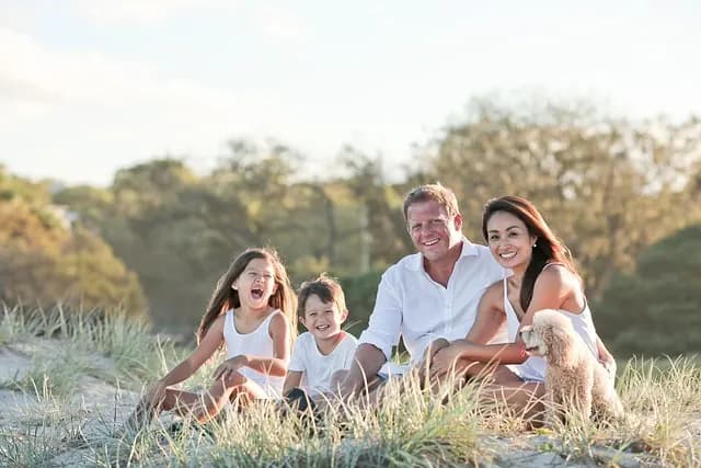 A family sitting together in beach grass in late afternoon light